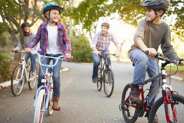 2 kids and their parents biking down the road together. 
