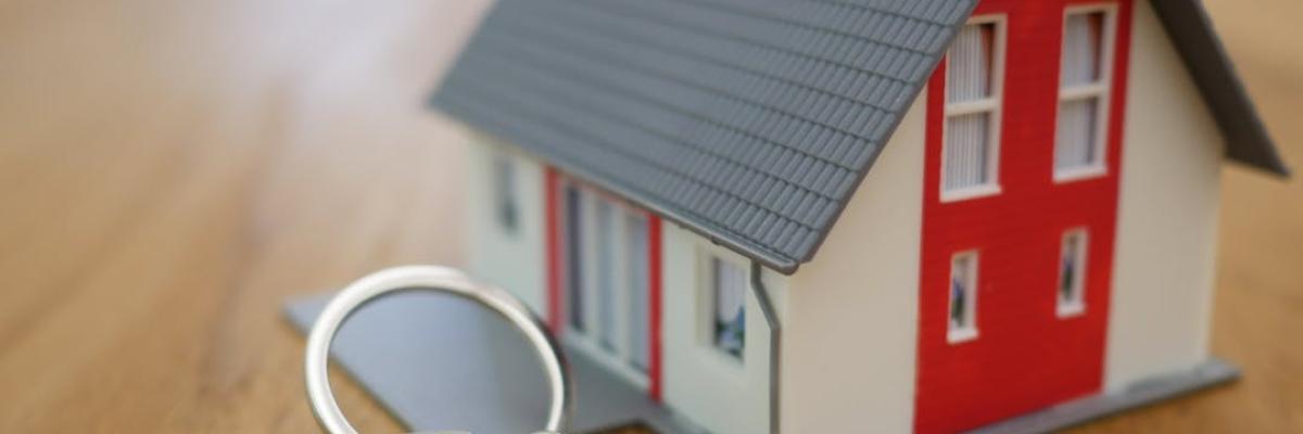 A small house keychain attached to keys on a table.