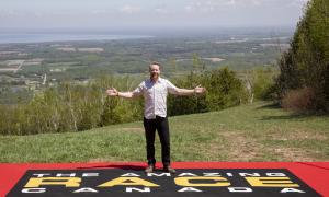 Jon Montgomery, host of The Amazing Race Canada standing atop Osler Bluff Ski Club with a panoramic view of Collingwood and Georgian Bay in the background