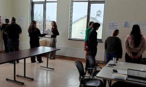Two groups of people looking at and discussing impact statements written on the wall