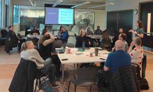 Groups of people sitting around tables looking at a speaker