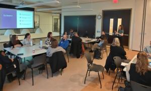 Groups of people sitting around tables looking at a speaker