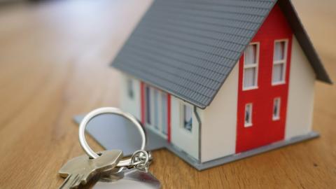 A small house keychain attached to keys on a table.